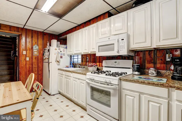 a kitchen with stainless steel appliances granite countertop a stove a refrigerator a white cabinets and white appliances