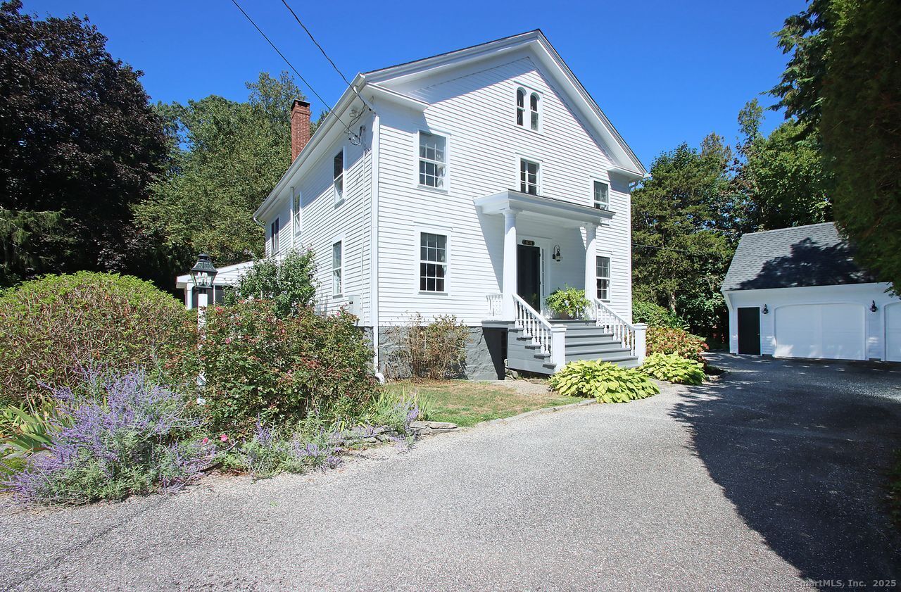 a view of a white house with a small yard and potted plants