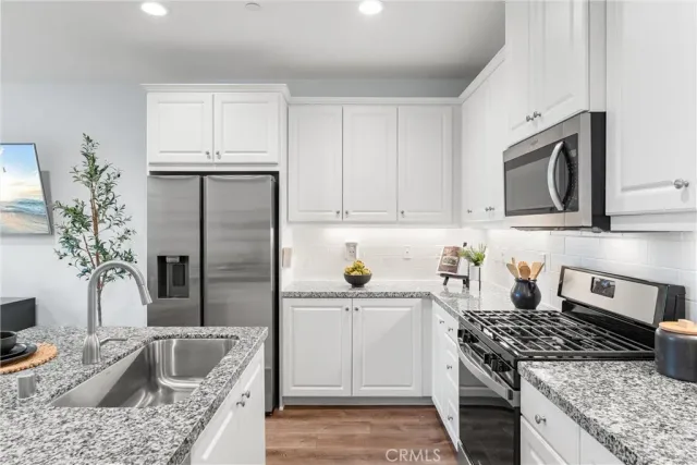 a kitchen with granite countertop kitchen island white cabinets and stainless steel appliances