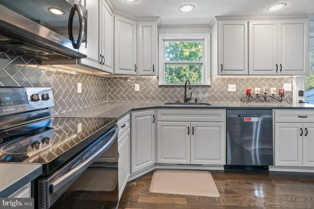 a kitchen with stainless steel appliances granite countertop a sink a stove a microwave and wooden cabinets
