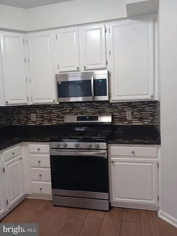 a kitchen with granite countertop white cabinets and stainless steel appliances
