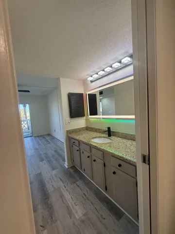 a bathroom with a granite countertop sink and a large mirror