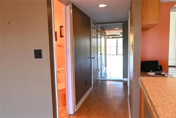 a view of a hallway with wooden floor and living room