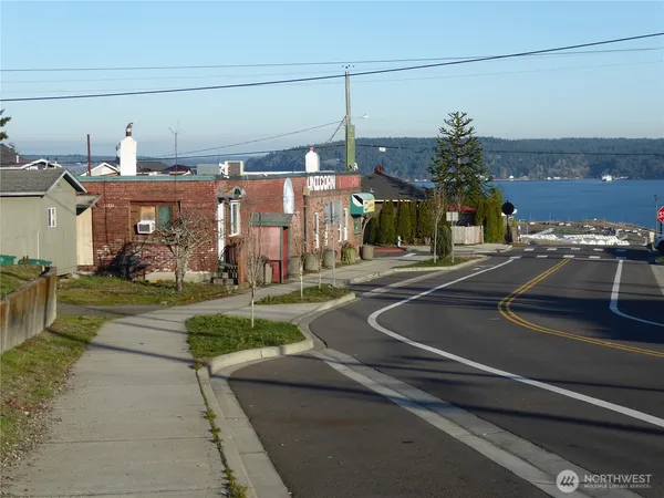 a view of a building with a yard and a car parked on the road