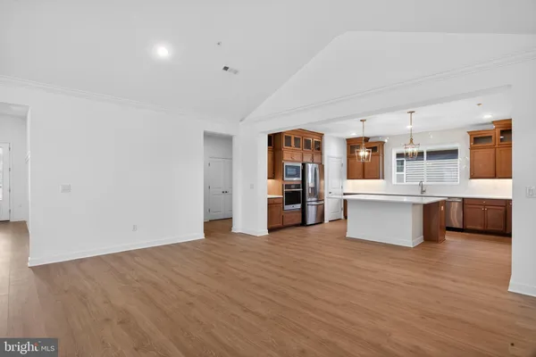 a large kitchen with stainless steel appliances a large counter top cabinets and wooden floor