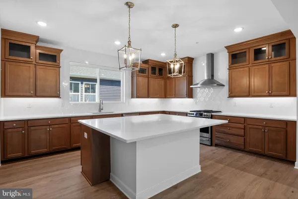 a kitchen with stainless steel appliances granite countertop a stove a sink dishwasher a refrigerator and a oven with wooden floor