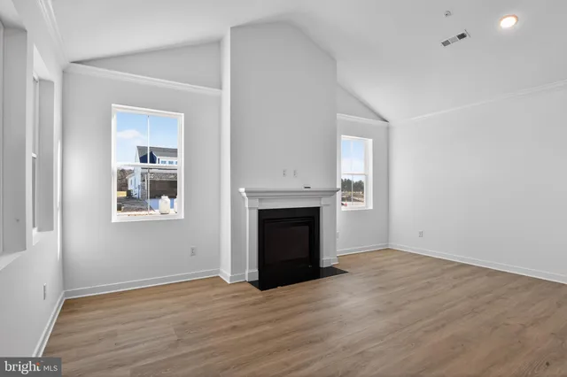 an empty room with wooden floor a fireplace and windows