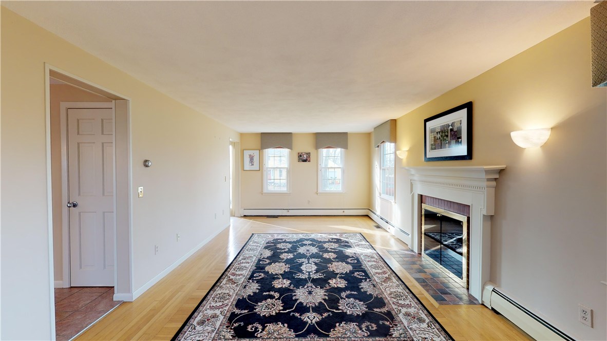 70 Timberline Road Warwick, RI 02886 - Photo 5 of 32 Front to back large living room with wood burning fireplace, hardwood floors, alabaster marble sconces and lovely window treatments