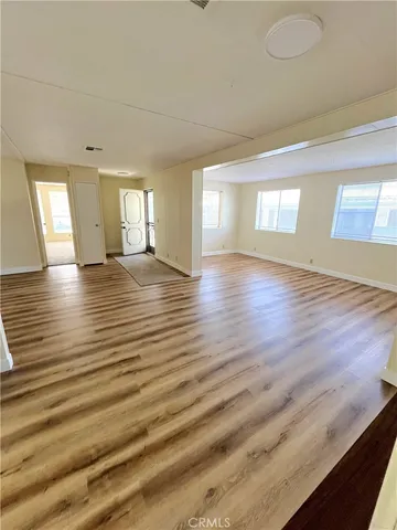 a view of an empty room with window and wooden floor