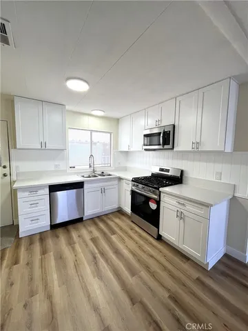 a kitchen with stainless steel appliances a sink a stove top oven a refrigerator and cabinets