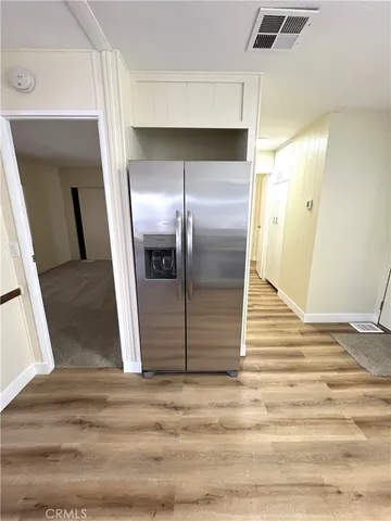 a view of a refrigerator in kitchen and an empty room