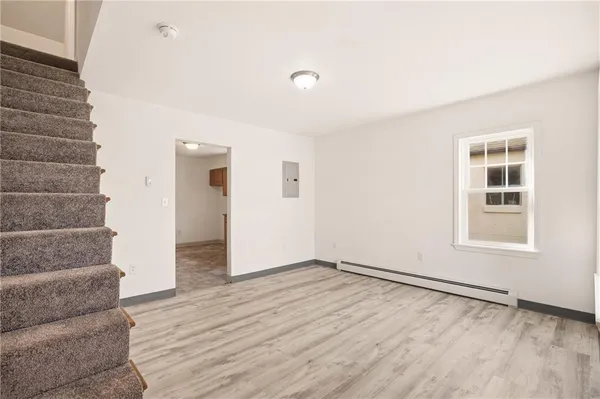 a view of an empty room with wooden floor and stairs