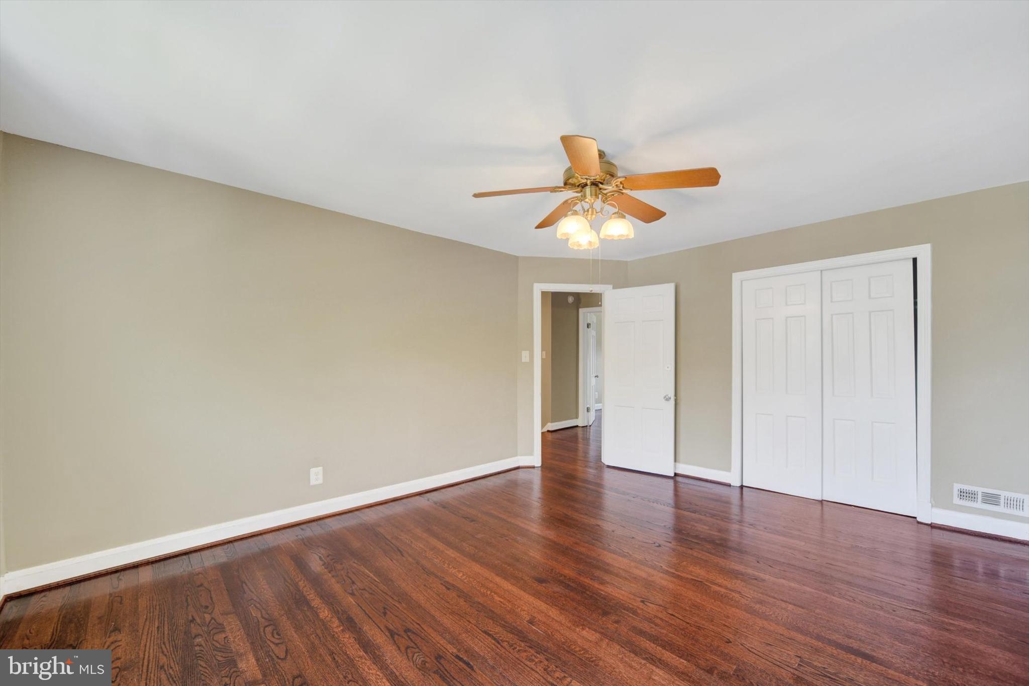 316 Lambeth Road Baltimore, MD 21228 - Photo 14 of 28 an empty room with wooden floor and ceiling fan