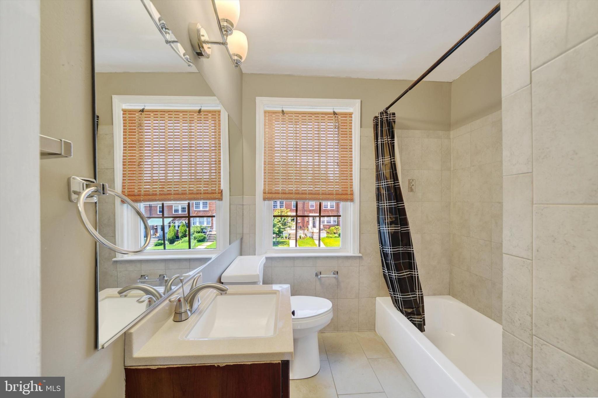 316 Lambeth Road Baltimore, MD 21228 - Photo 19 of 28 a bathroom with a sink a mirror a window and a shower