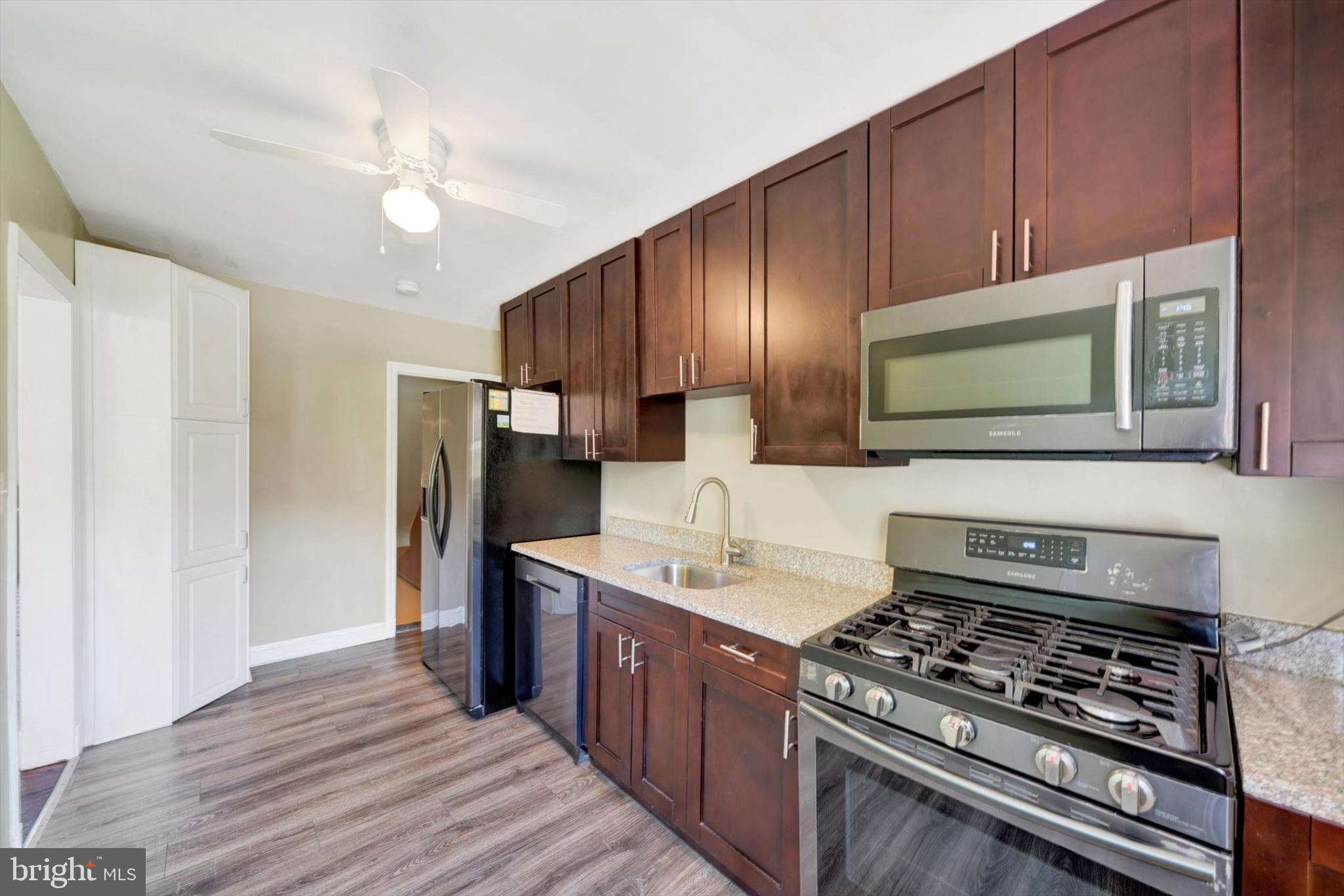 316 Lambeth Road Baltimore, MD 21228 - Photo 10 of 28 a kitchen with stainless steel appliances granite countertop a stove a sink dishwasher and a refrigerator with wooden floor