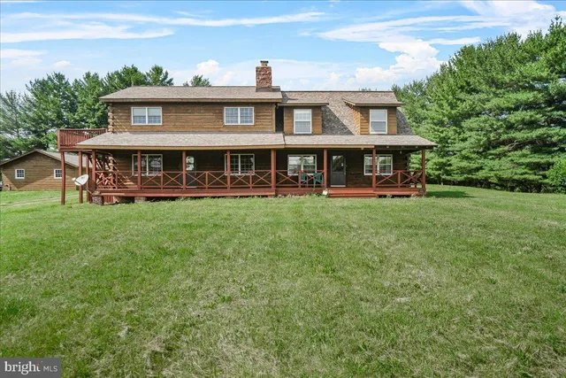 a view of a house with a big yard and large trees