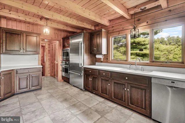 a large kitchen with kitchen island granite countertop a large stove a sink dishwasher and wooden cabinets