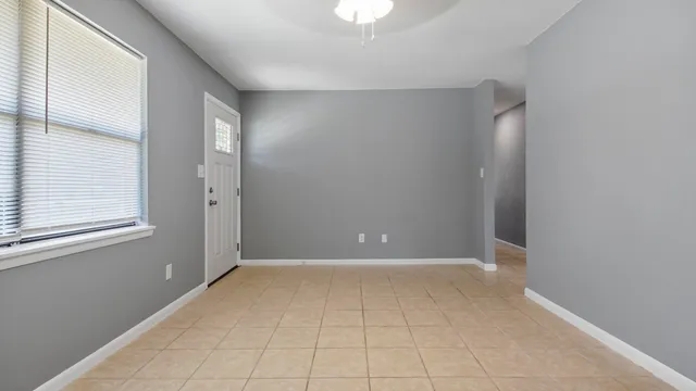 a view of an empty room with window and chandelier fan