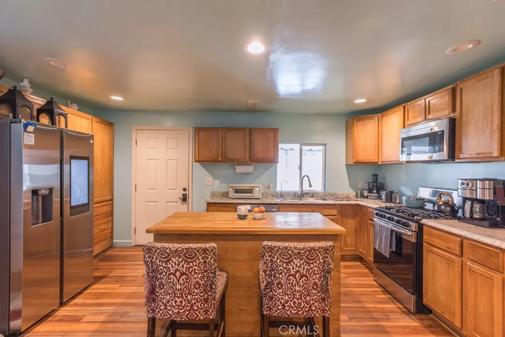 23500 The Old Road, Unit 35 Newhall, CA 91321 - Photo 6 of 43 a kitchen with stainless steel appliances granite countertop a sink a stove a refrigerator cabinets and a dining table with wooden floor