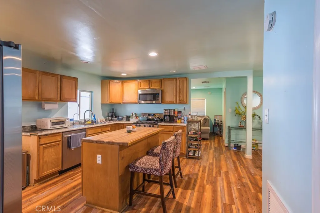23500 The Old Road, Unit 35 Newhall, CA 91321 - Photo 8 of 43 a kitchen with stainless steel appliances granite countertop a stove a sink dishwasher and a refrigerator with wooden floor