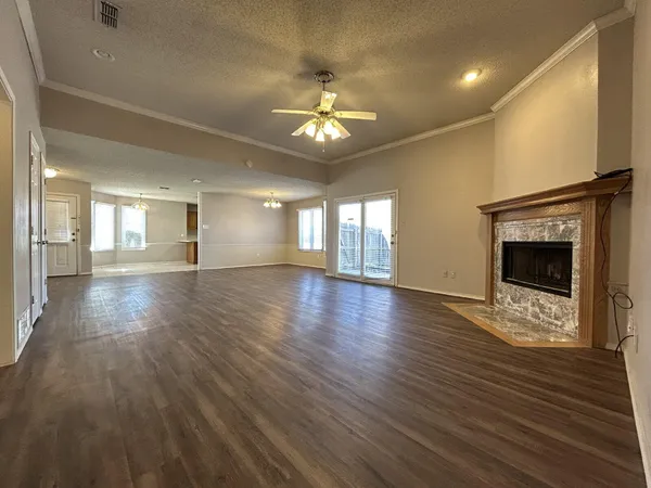 an empty room with wooden floor fireplace and windows