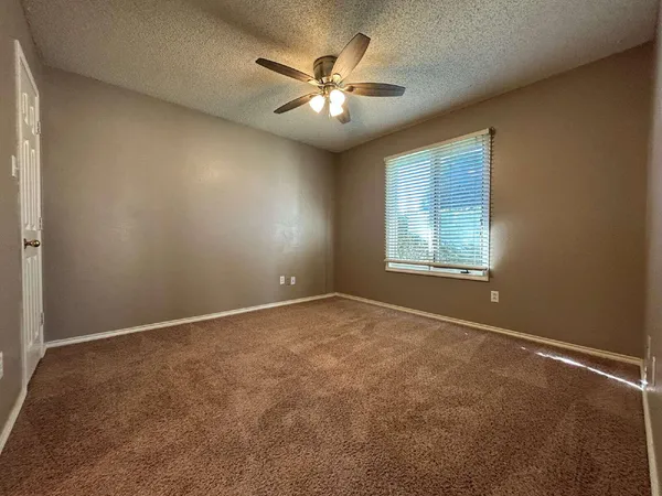 an empty room with windows and ceiling fan