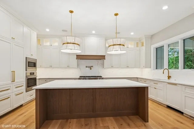 a kitchen with kitchen island granite countertop a sink a counter space appliances and cabinets