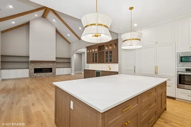 a large kitchen with kitchen island a stove a sink a center island and wooden floor