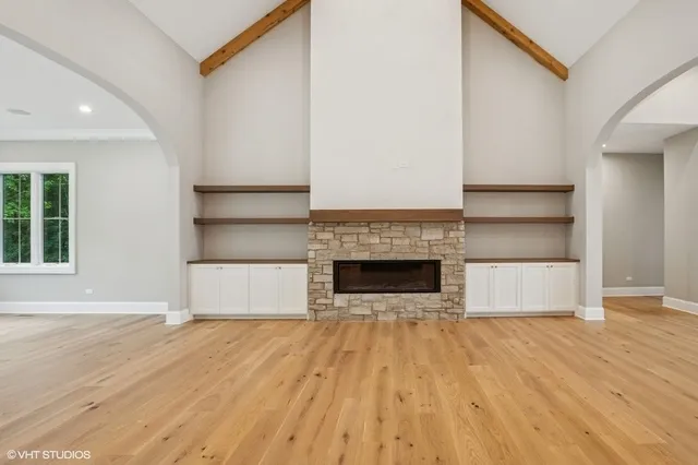 a view of an empty room with wooden floor and a fireplace