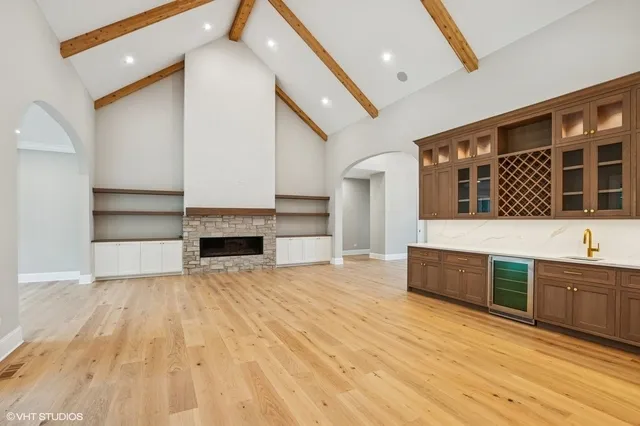 a view of an empty room with wooden floor and a kitchen