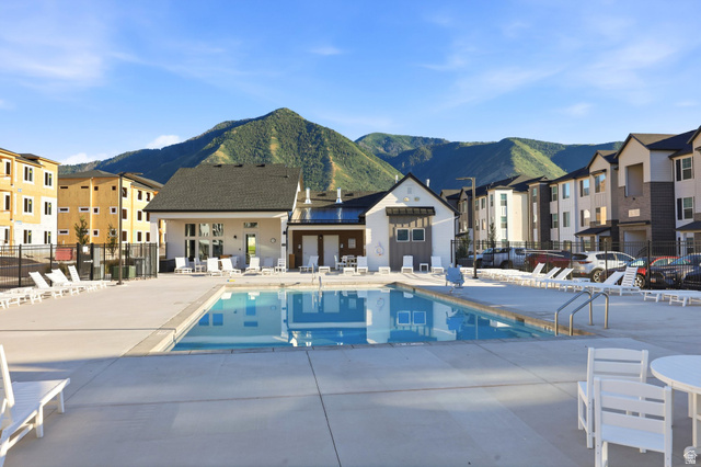 4646 Alder Drive, Unit 223 Mapleton, UT 84664 - Photo 23 of 35 Expansive outdoor pool area with surrounding concrete decking, flanked by modern multi-story residential buildings and a clubhouse structure, all set against a prominent mountain backdrop