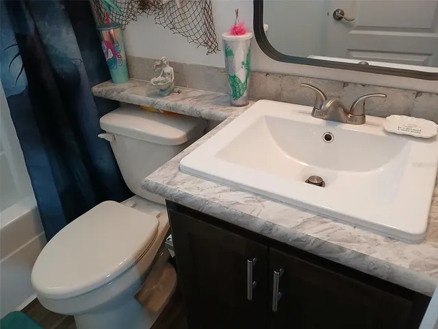 a bathroom with a granite countertop toilet sink and mirror