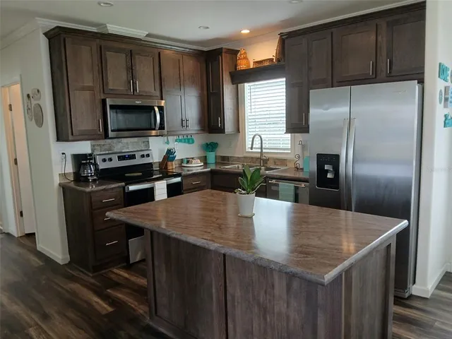 a kitchen with kitchen island a counter space a sink appliances and cabinets