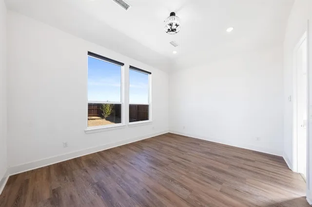 a view of an empty room with a window and wooden floor