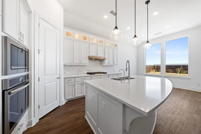 a kitchen with kitchen island a counter space a sink appliances and cabinets