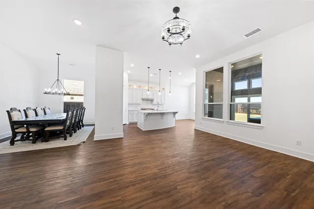 a view of a dining room and livingroom with furniture wooden floor a chandelier