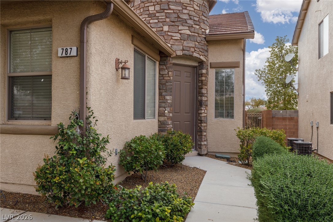 787 Rise Canyon Drive Henderson, NV 89052 - Photo 2 of 22 A welcoming stone facade entrance greets visitors, complemented by well-maintained shrubbery and a convenient pathway.