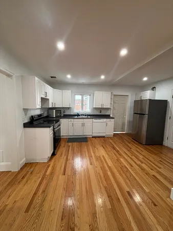 a large kitchen with stainless steel appliances granite countertop a large counter top and wooden floors