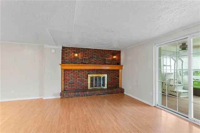 a view of an empty room with wooden floor and windows