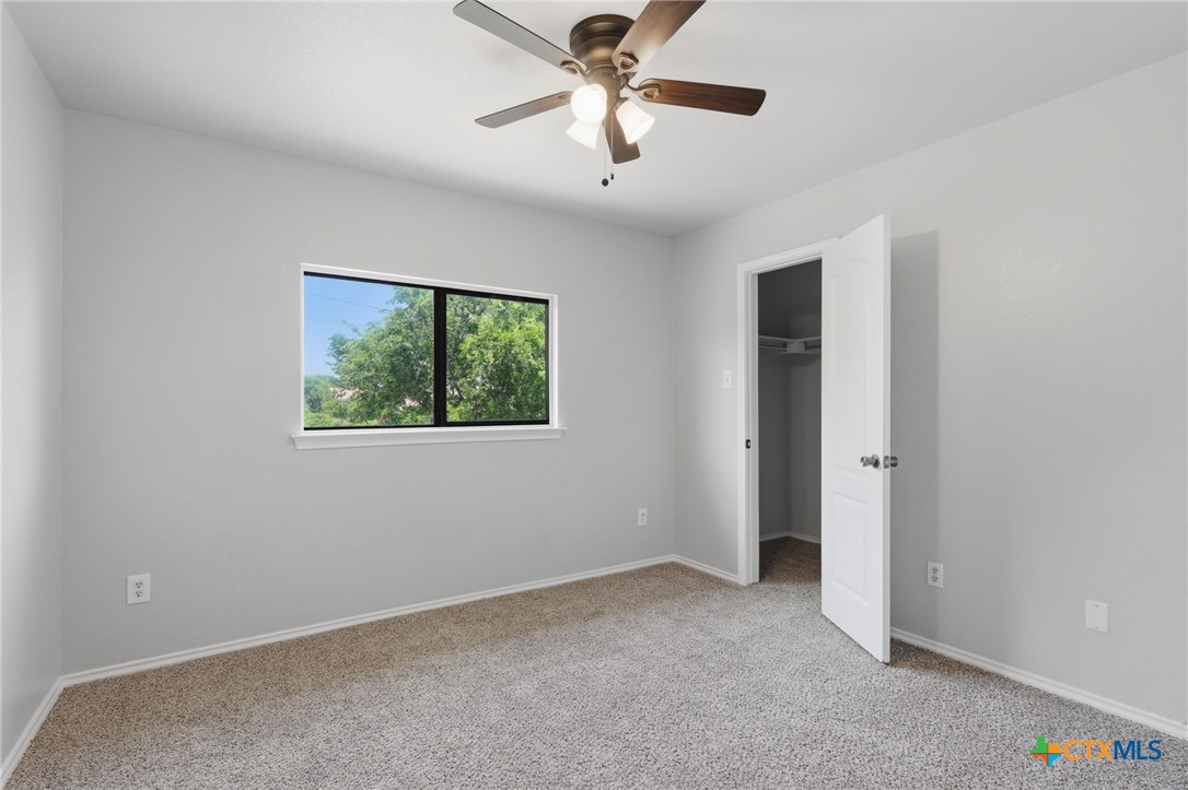 8716 Starview Street Temple, TX 76502 - Photo 24 of 36 Comfortable carpeted bedroom with a ceiling fan and a window.