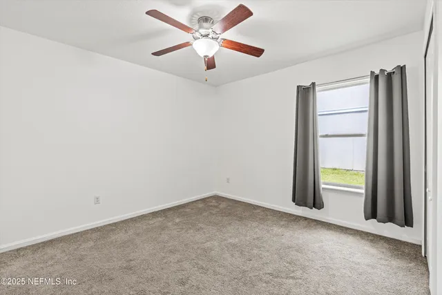 an empty room with a window and a ceiling fan