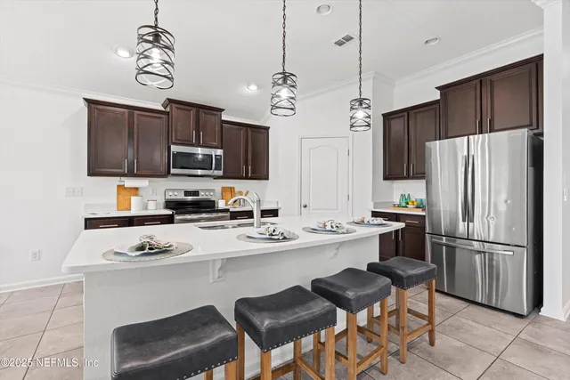 a kitchen with stainless steel appliances a stove refrigerator a sink a stove a microwave and chairs