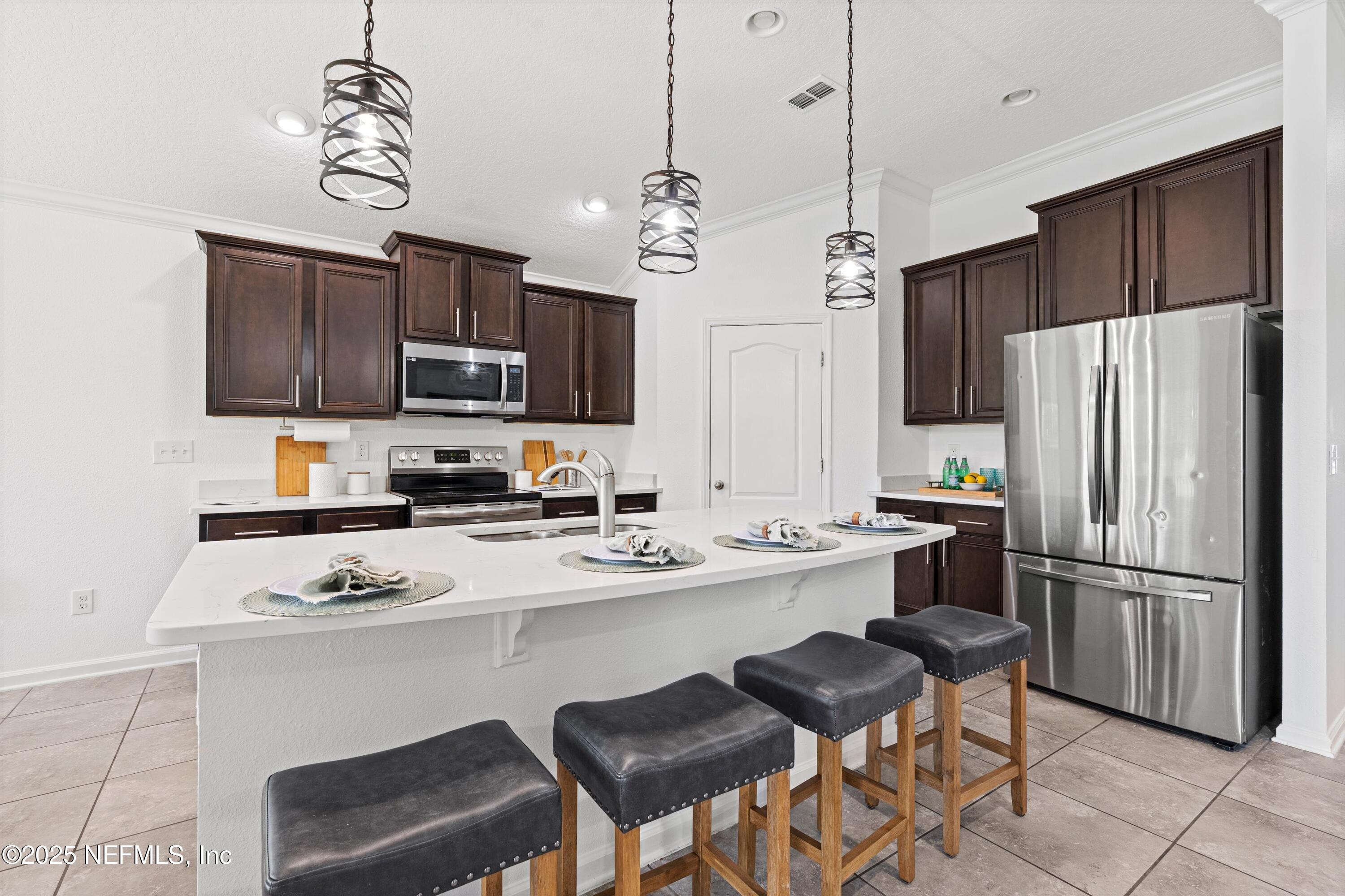 12264 Sacha Road Jacksonville, FL 32226 - Photo 7 of 32 a kitchen with stainless steel appliances a stove refrigerator a sink a stove a microwave and chairs