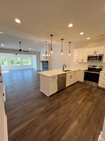 a large kitchen with stainless steel appliances a large counter top a stove a sink and a refrigerator