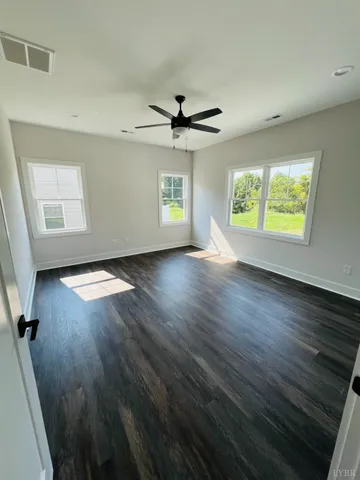 an empty room with windows and a ceiling fan