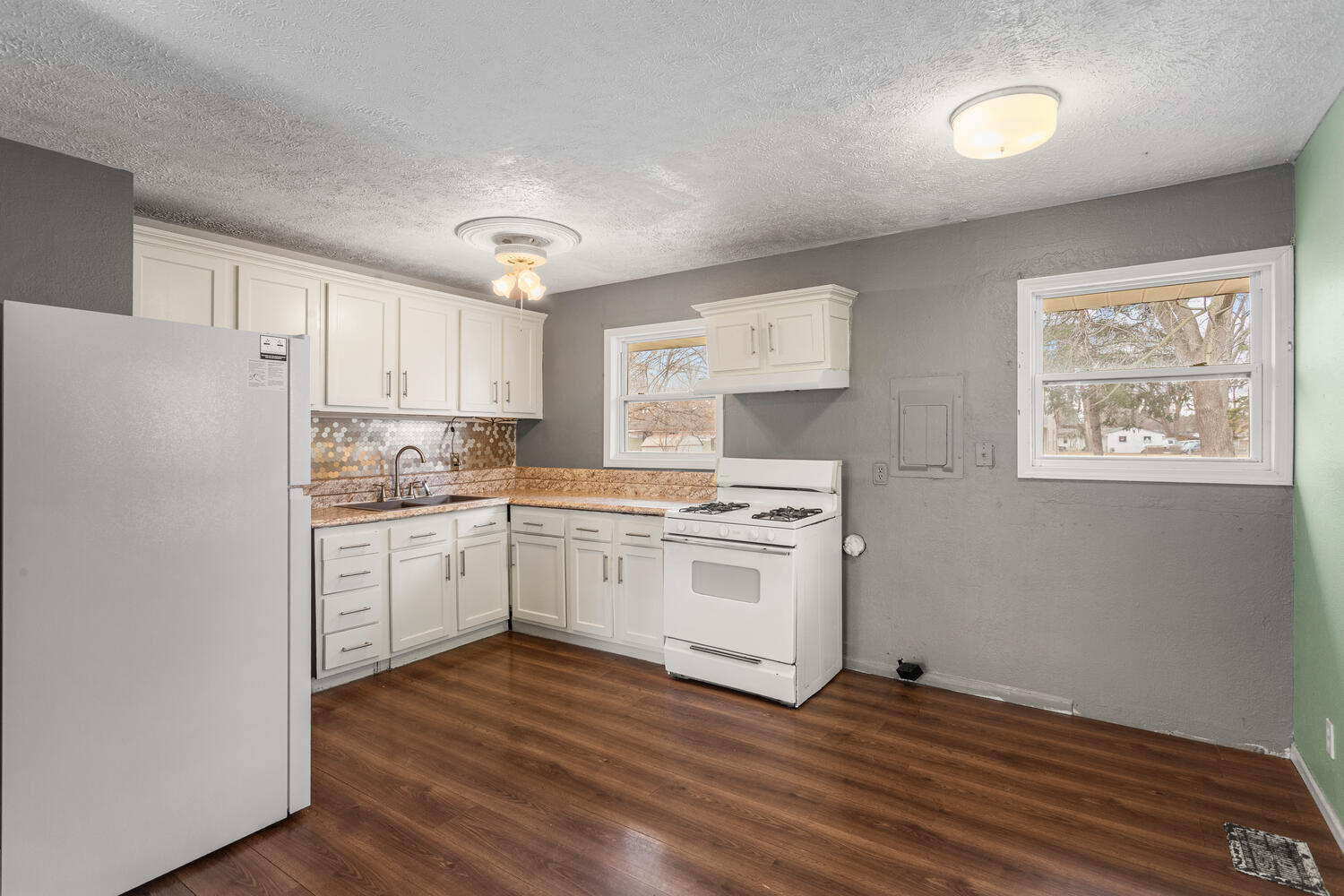 1468 Mather Drive Rantoul, IL 61866 - Photo 12 of 23 a kitchen with granite countertop a refrigerator stove and white cabinets with wooden floor