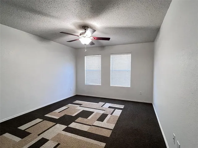 an empty room with windows and ceiling fan