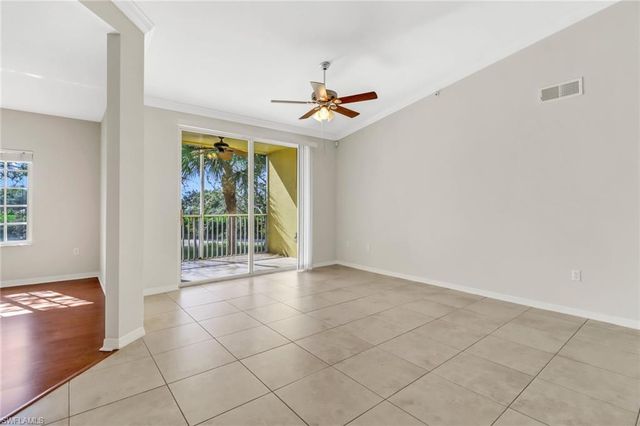 an empty room with windows and chandelier fan
