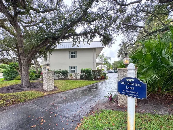 a sign board with a yard and large trees