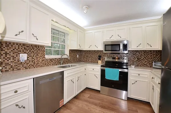 a kitchen with granite countertop white cabinets and black stainless steel appliances